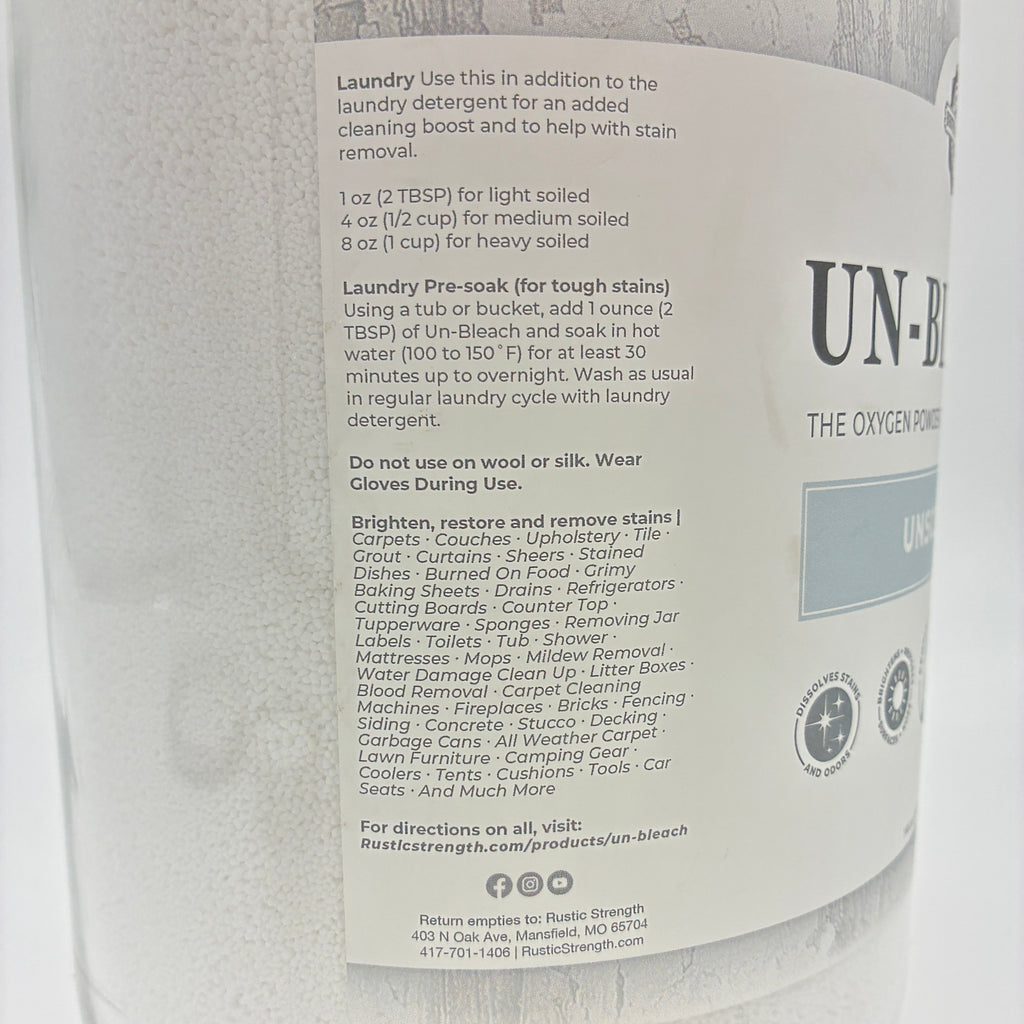 A close-up of a large white glass bottle of Unbleach laundry cleaner, showing the front label with product details and branding.