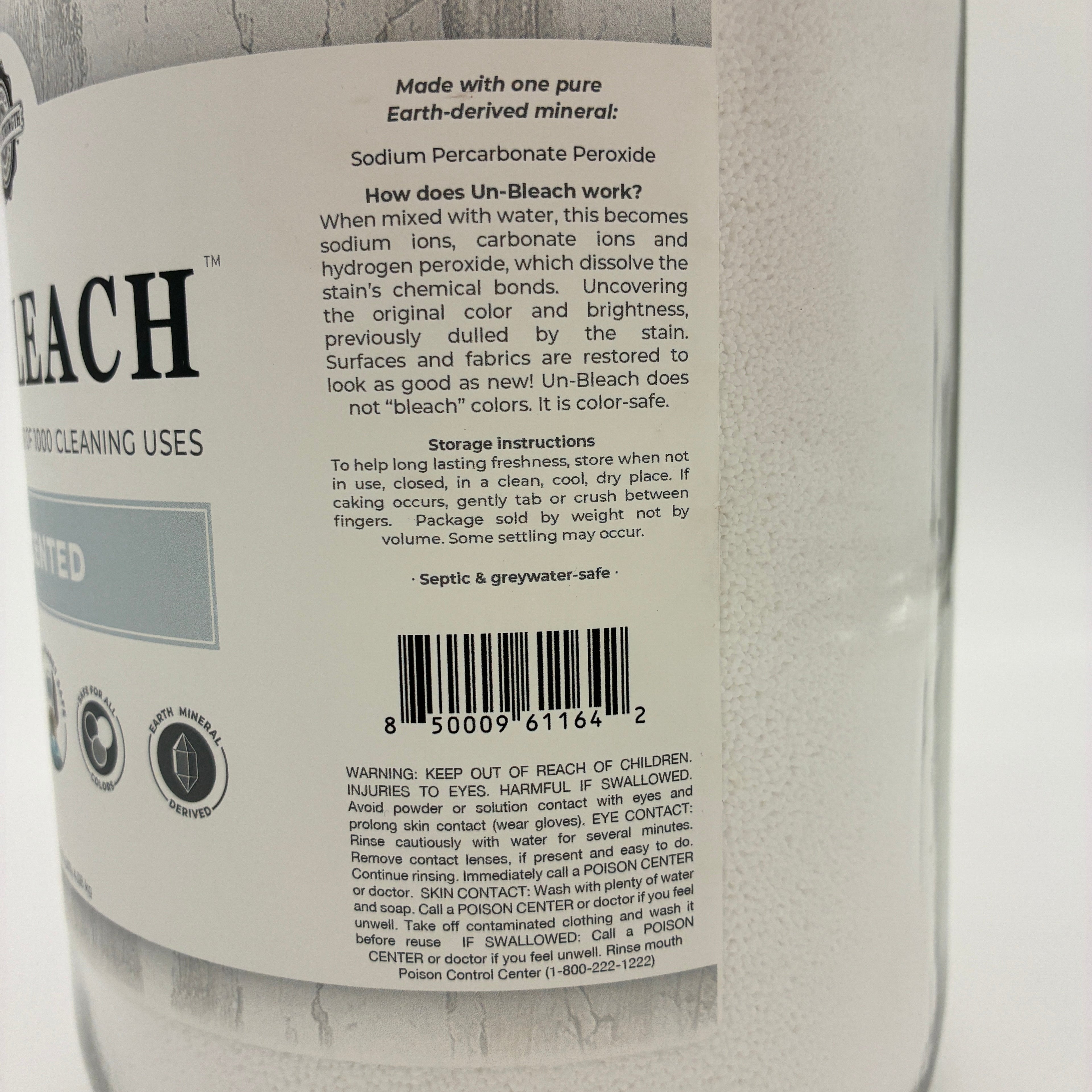A close-up of the back label of a large white glass bottle of Un-Bleach cleaning powder, showing product details, instructions, and a barcode.